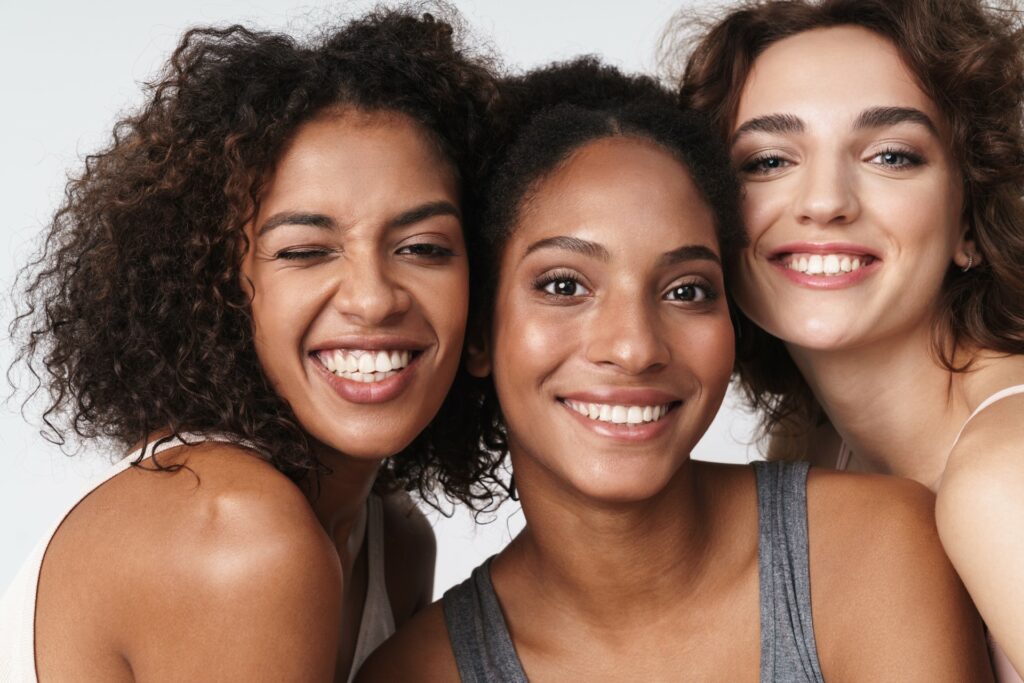 three smiling happy women faces skin types