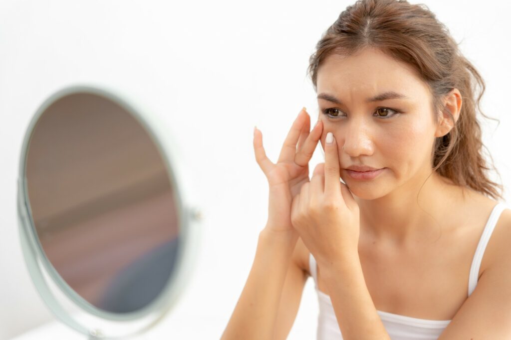 woman looking in mirror pores magnify